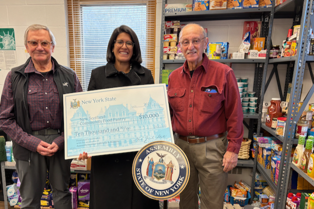 Ivan Gotham (L) NS Community Food Pantry Executive Director, and Dennis Ulion (R) Treasurer, receive a check from Assemblymember Gabriella Romero.
