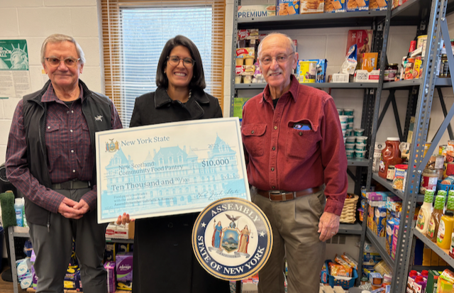 Ivan Gotham (L) NS Community Food Pantry Executive Director, and Dennis Ulion (R) Treasurer, receive a check from Assemblymember Gabriella Romero.